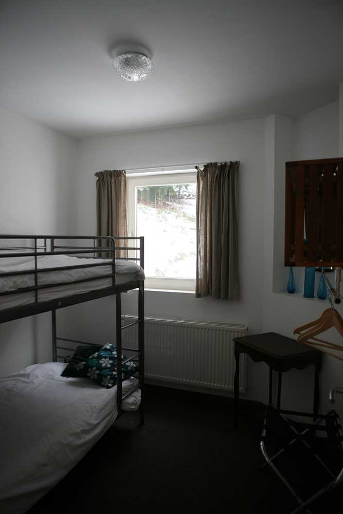 Slaapkamer op het tussenverdiep met dubbelbed en stapelbed en badkamer